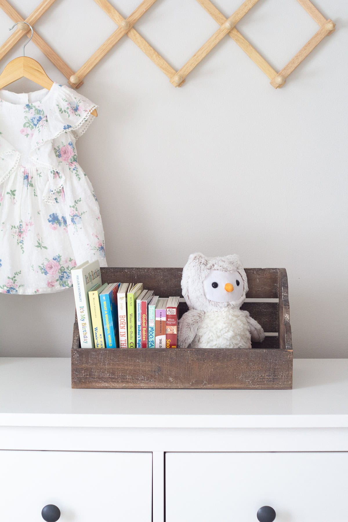 A box-shelf storage bin from Hobby Lobby filled with board books and resting on top of a dresser.