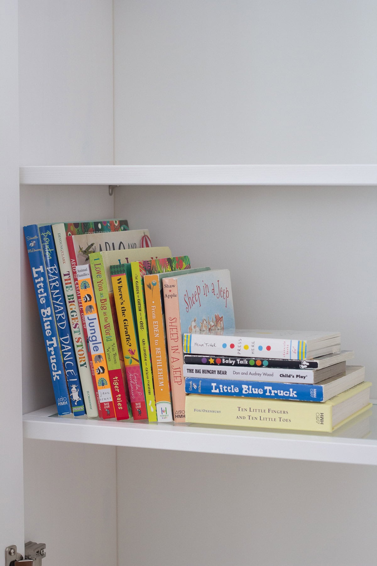 A variety of colorful board books on a built-in bookshelf.