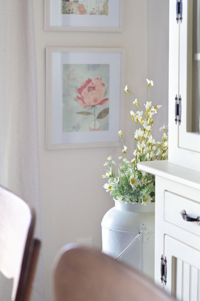 Faux flowers in a watering can and floral prints in a kitchen.