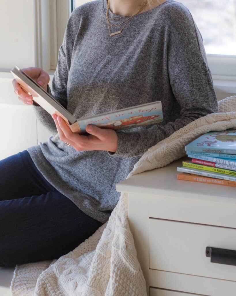 Woman sitting and holding an open board book.