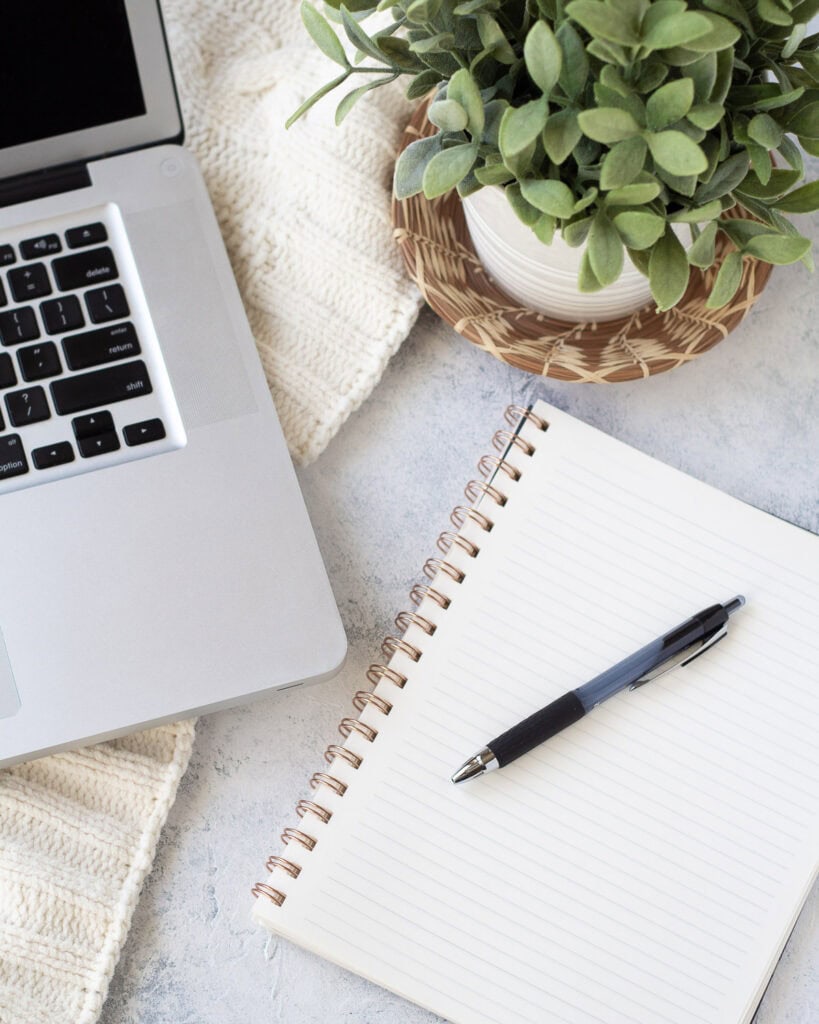A laptop, empty notebook and black pen.